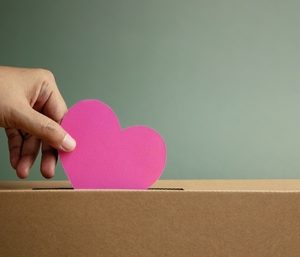 Donation,Concept.,Hand,Droping,A,Pink,Paper,Heart,Into,A