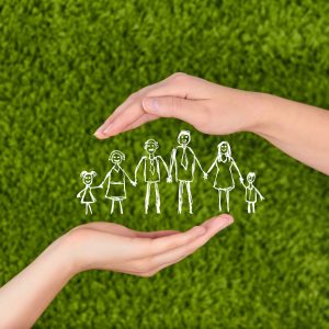 due mani che proteggono una famiglia disegnata su un prato verde