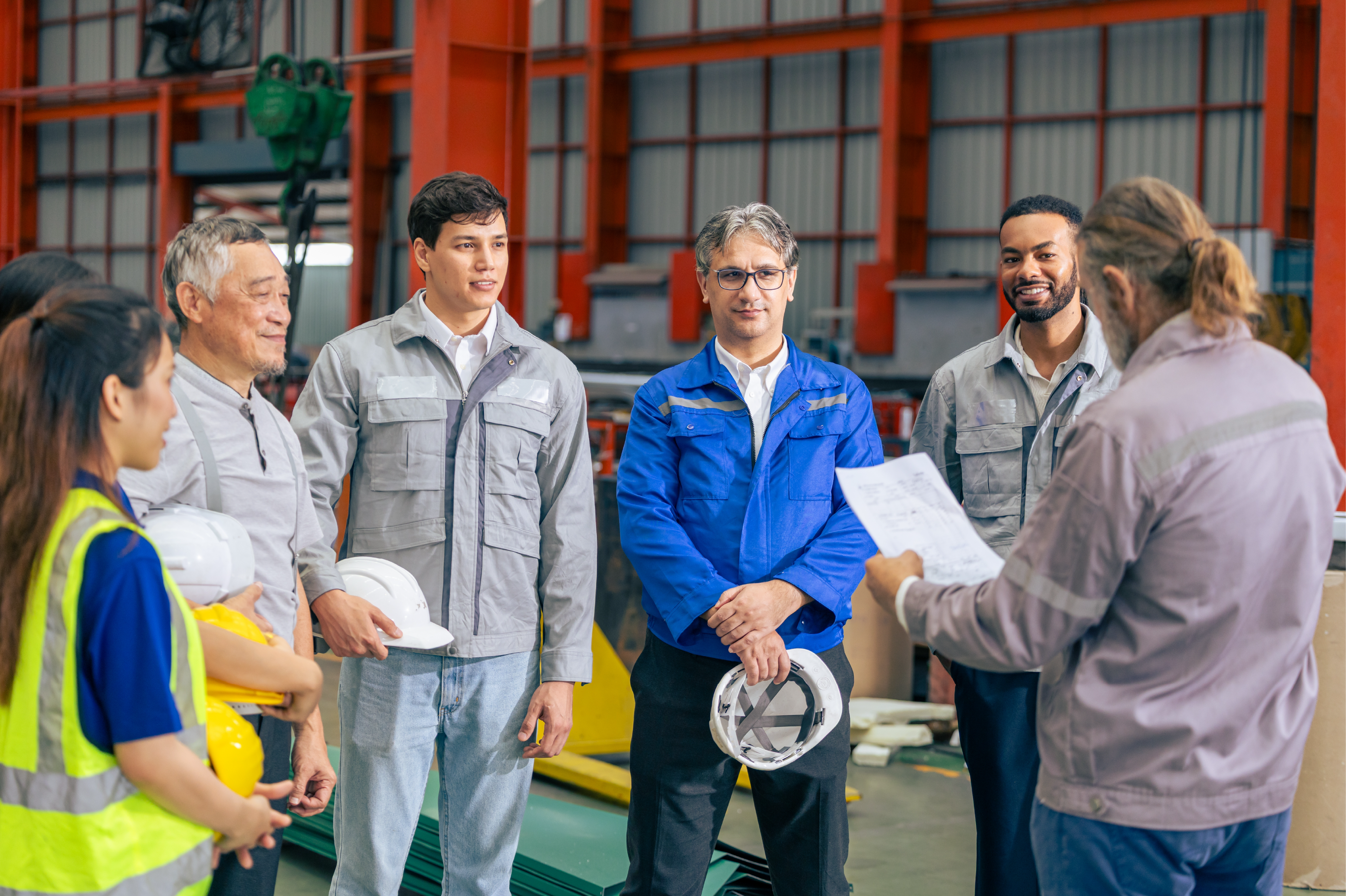 Formazione sulla sicurezza sul lavoro in azienda con team di operai e supervisore durante briefing operativo
